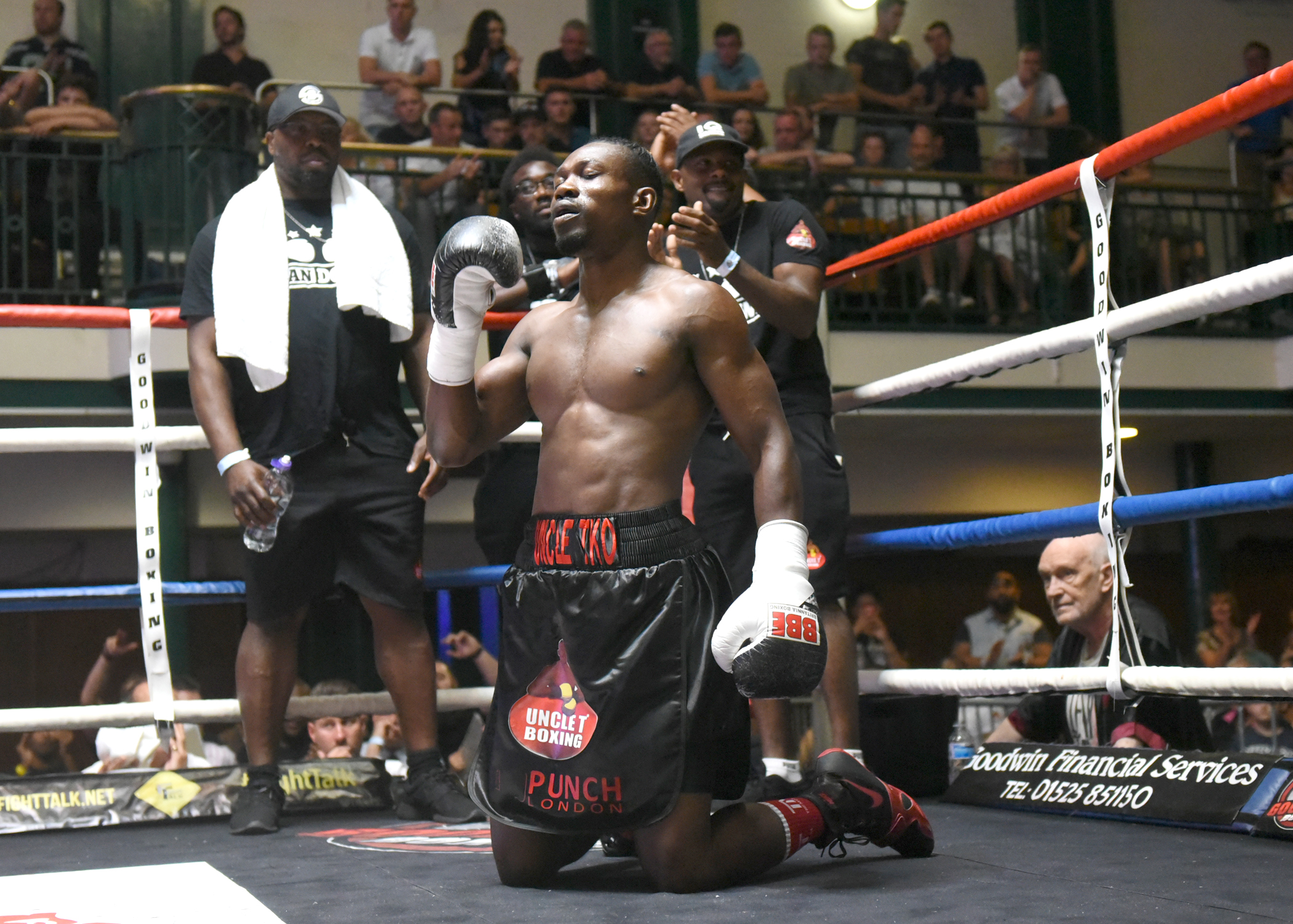 Tunji Ogunniya on one knee in the ring after a win